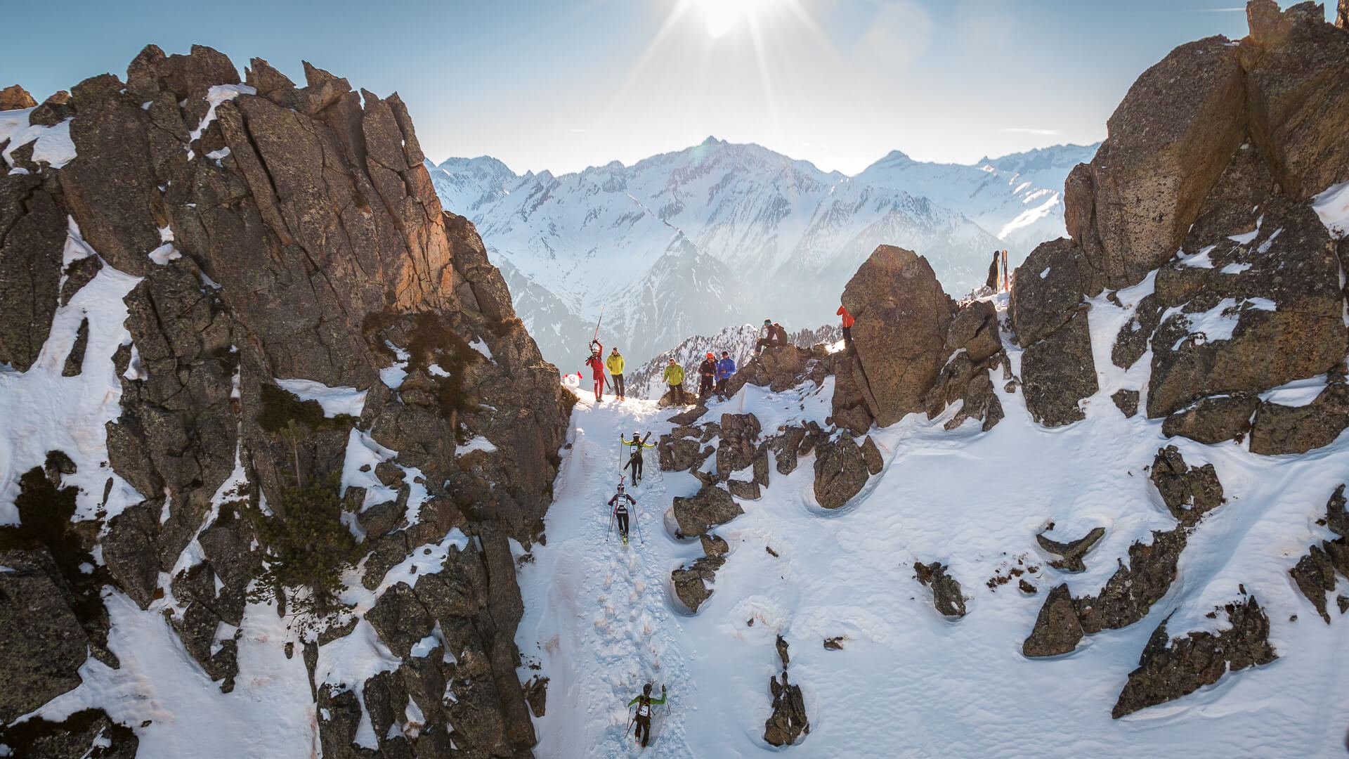 Coureurs de l'Altitoy 2017, skis sur le sac, dans un couloir enneigé entre les rochers, vus d'hélicoptère
